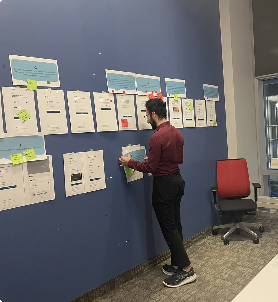Keyan pins printed quote screens and sticky notes to a blue wall for the focus group