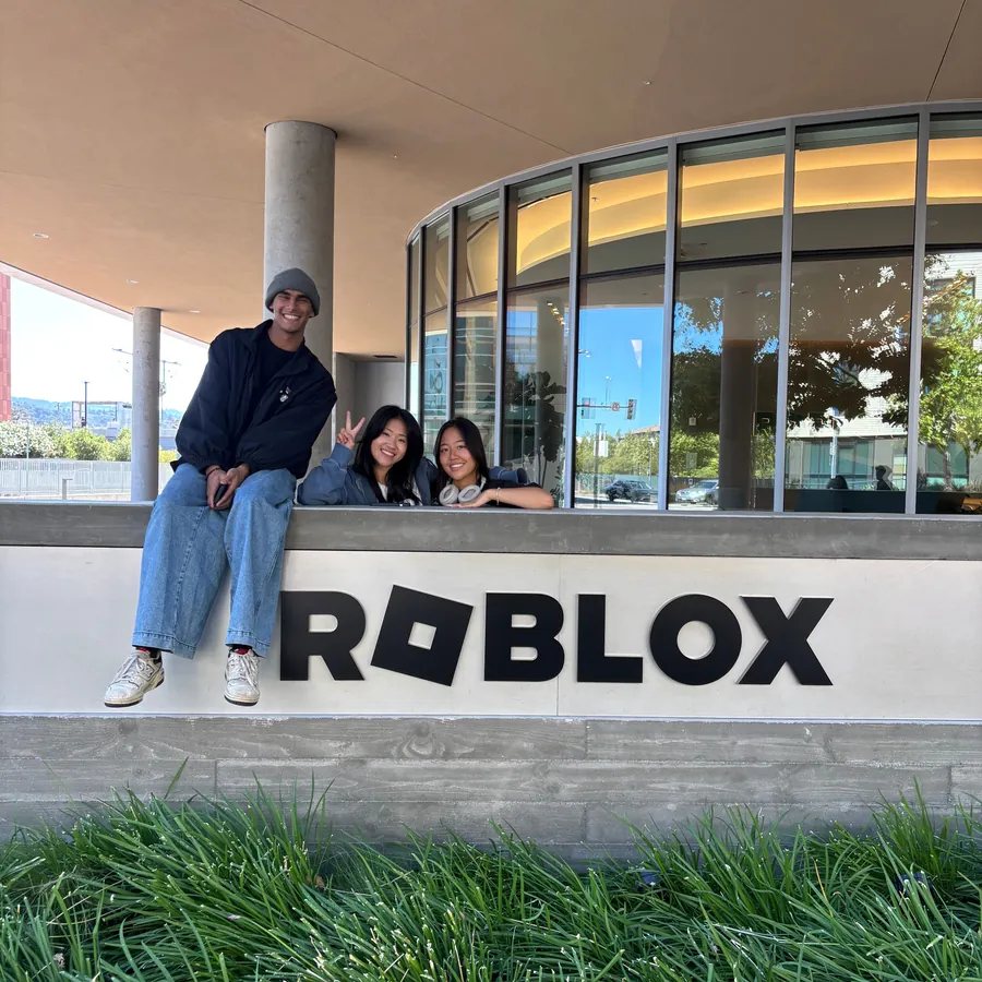 Keyan and two friends perched on the Roblox sign outside the office