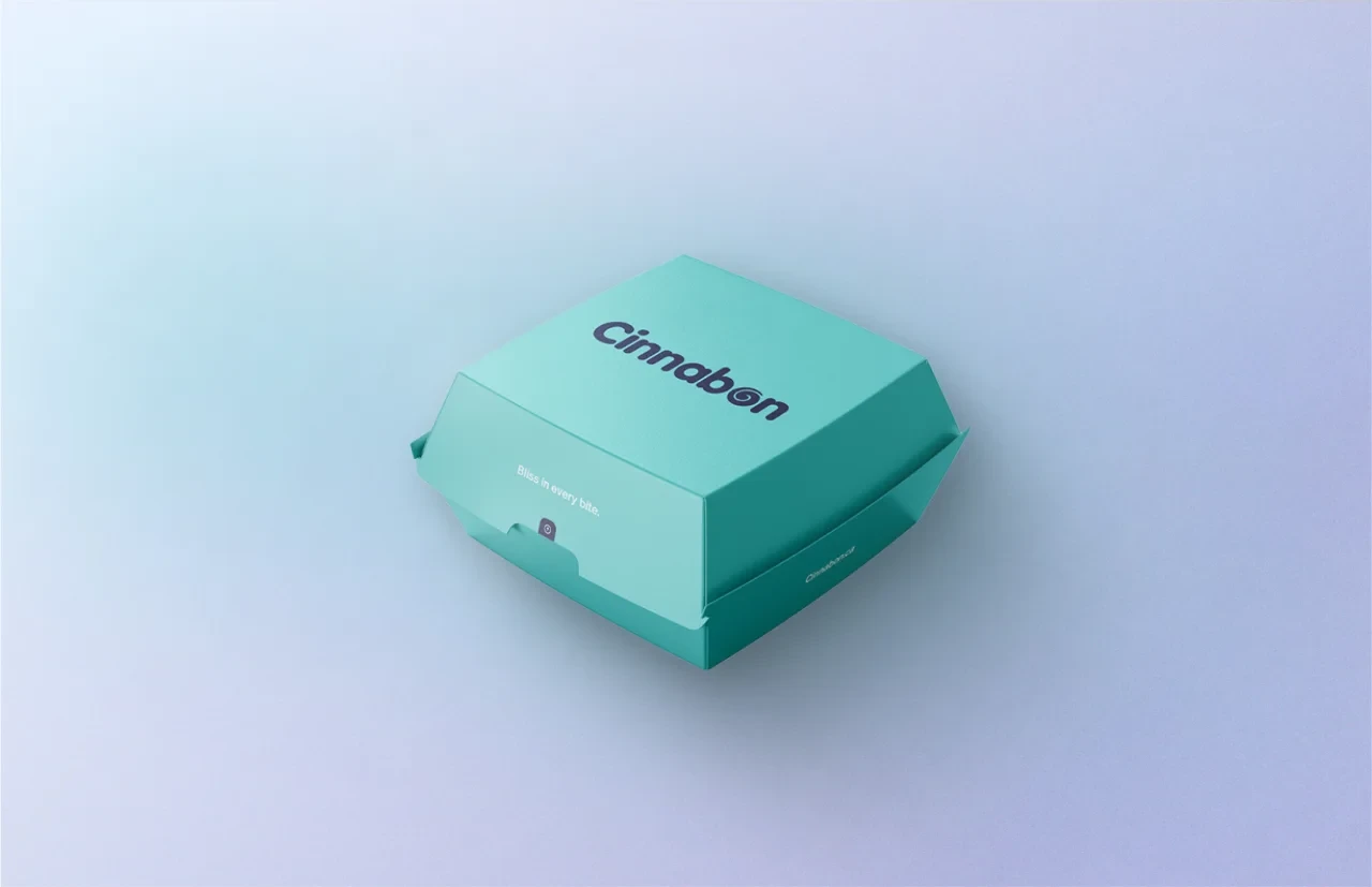 A teal Cinnabon takeout box on a soft blue ground
